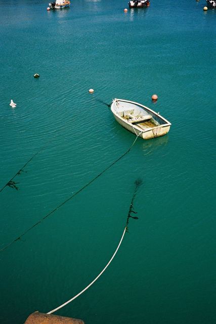 A small white boat on deep teal water, seen from above