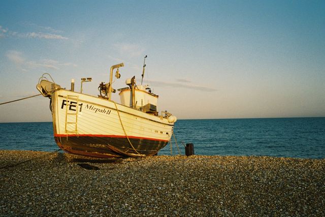 A wooden fishing boat on a beach at golden hour