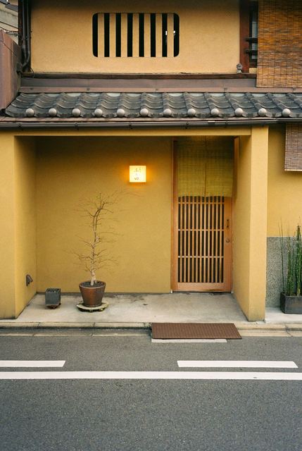 An ochre doorway with a lantern and a potted tree