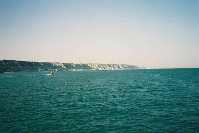 Teal sea with white cliffs on the horizon